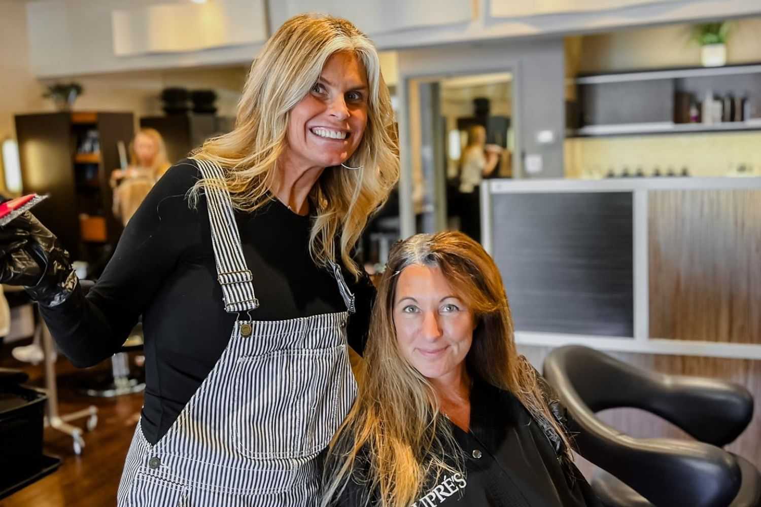 Hairstylist with smiling client in a modern salon.