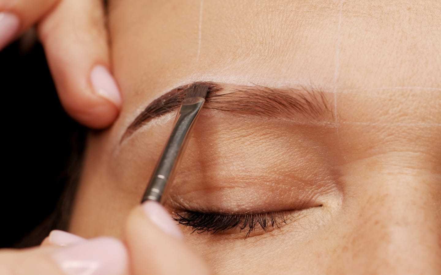 Eyebrow being shaped with a brush, showing detailed grooming process.