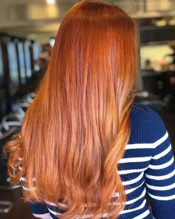 Long, vibrant red hair styled in soft waves at a salon.