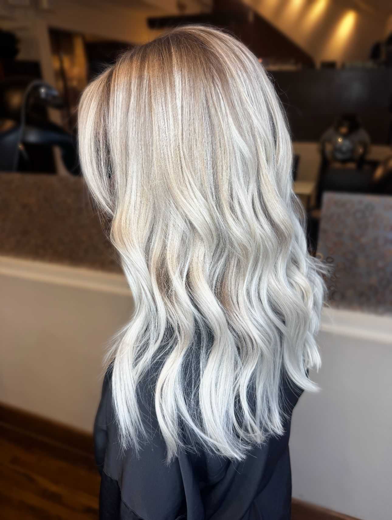 Wavy blonde hair with highlights styled in loose curls in a salon setting.