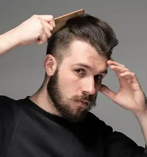 Man combing his neatly styled hair with a focused expression.