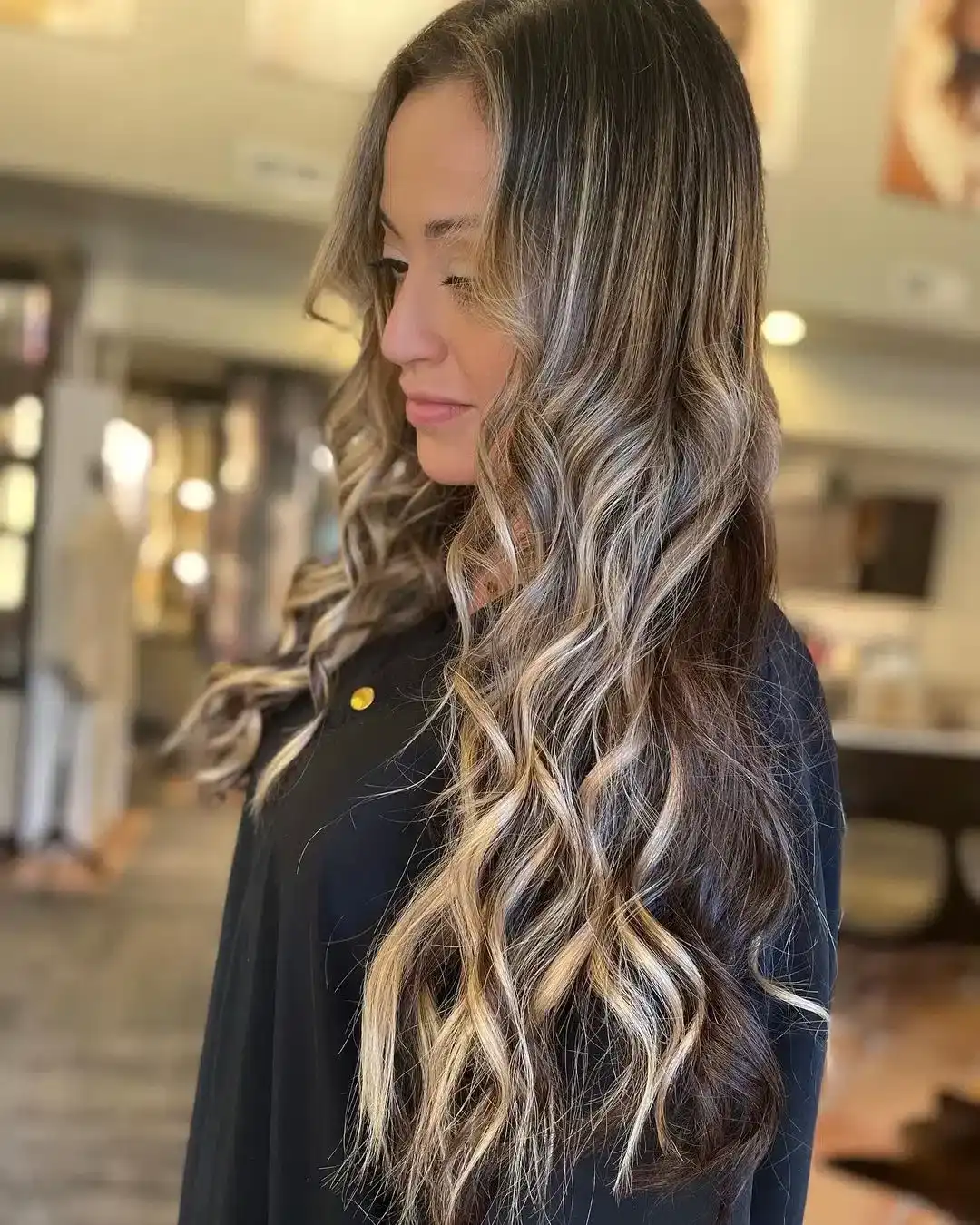 Woman with long, wavy, highlighted hair in a salon setting.