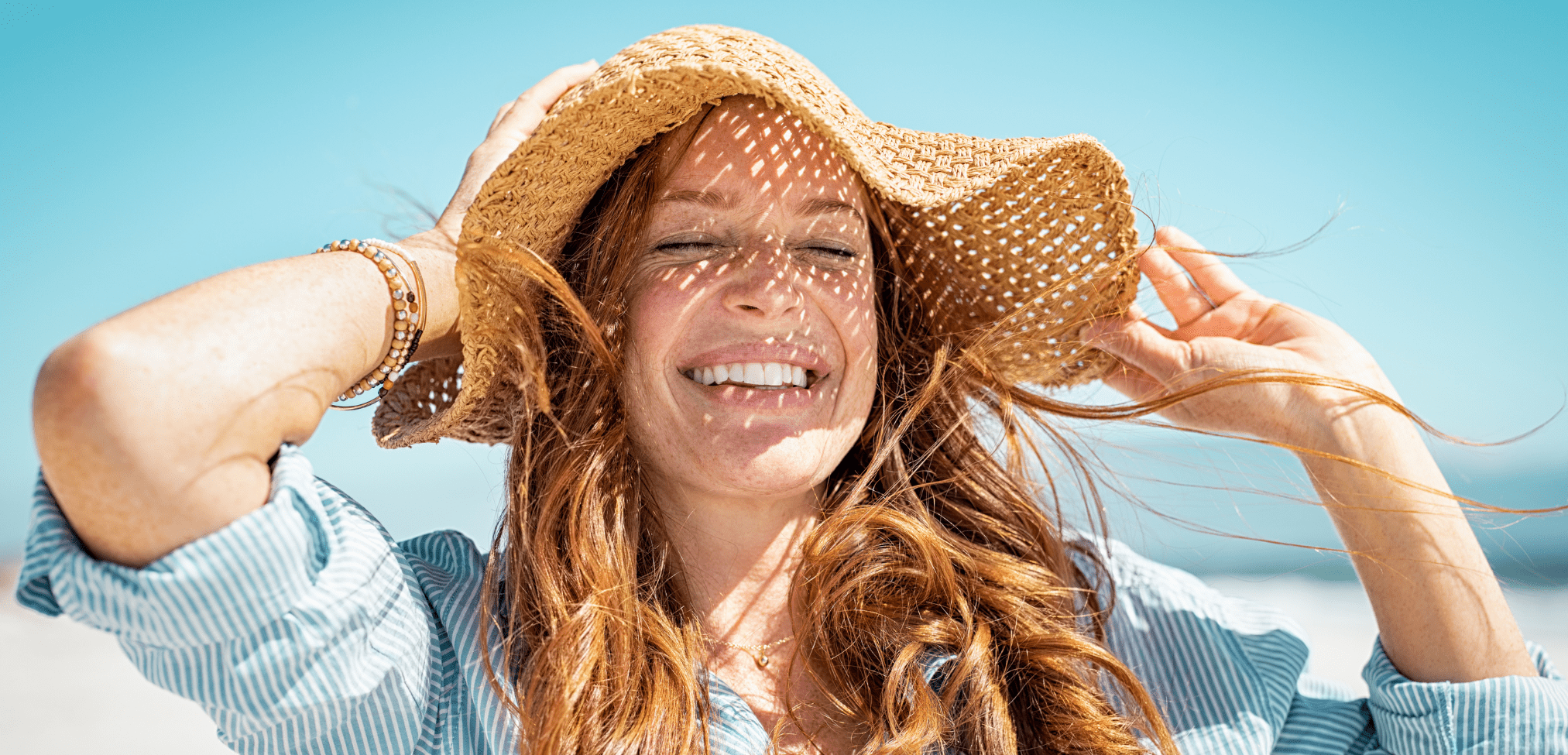 Woman with beach hat smiling | Dupre's Salon and Day Spa Woman at beach | Dupre's Salon and Day Spa